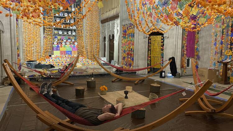 A person rests in a hammock at Green-Wood Cemetery's Dia de Muertos ofrenda.
