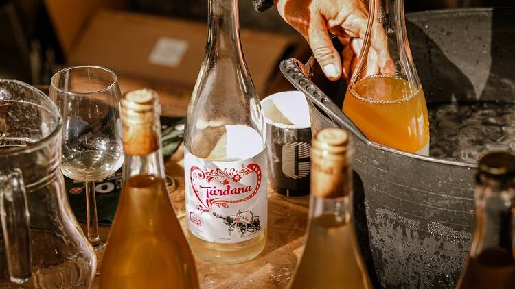 A table with orange wines on the table and in buckets