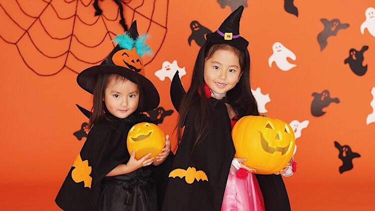 Two little girls dressed in witches outfits for halloween trick or treating