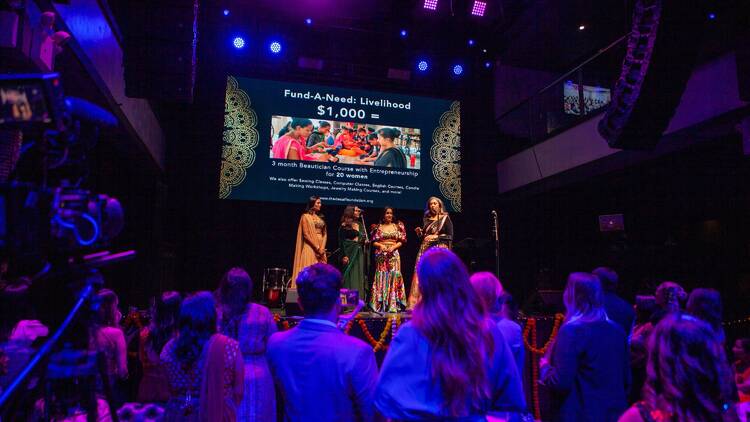 Women on stage in front of a crowd for a fundraising event