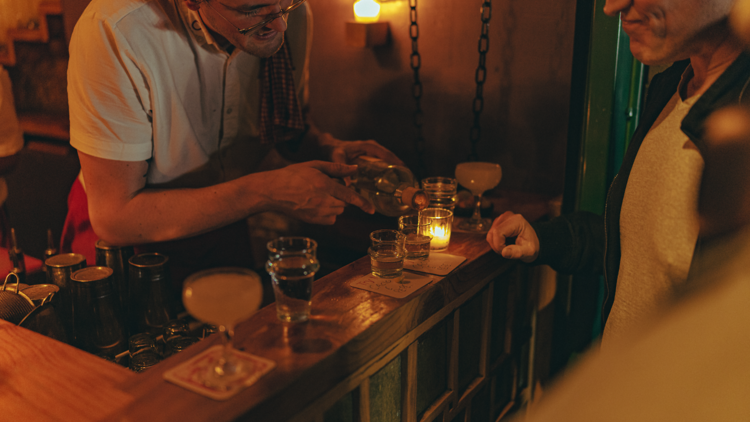 A bartender pouring drinks on a bar