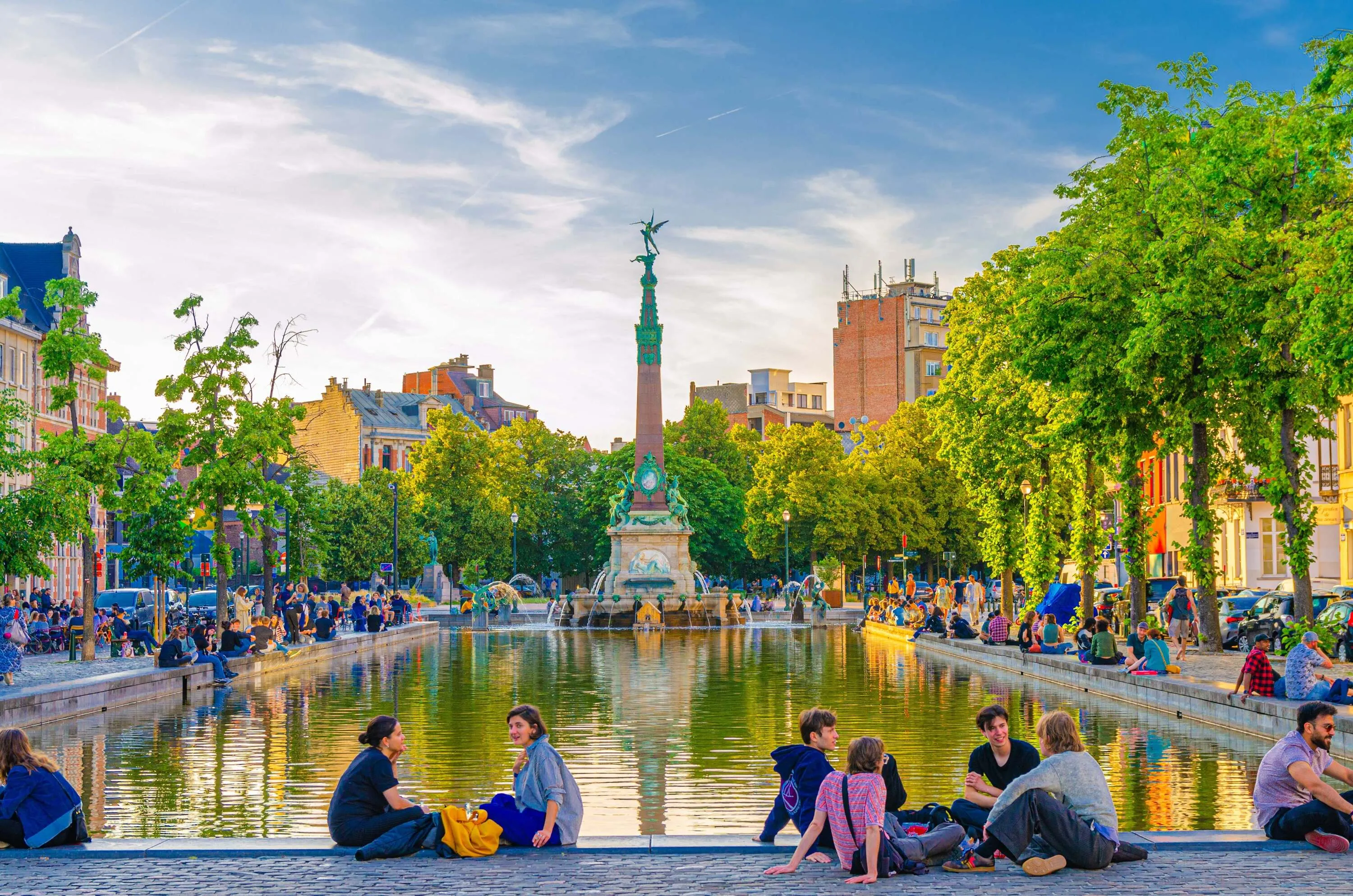 young people tourists sit near small pound with Fontaine Anspach fountain at Old Port Fish market square Vismarkt in old town Brussels city historical center