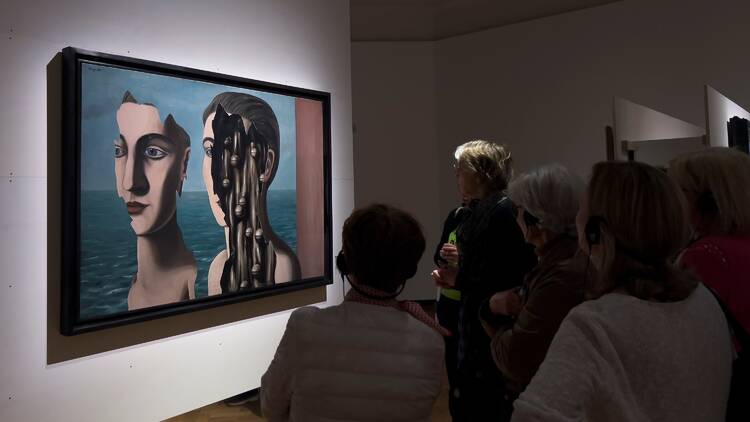 Visitors look at paintings of surrealist artists during the exhibition "Surrealism in Belgium" at the Bozar Museums in Brussels, Belgium on April 6, 2024