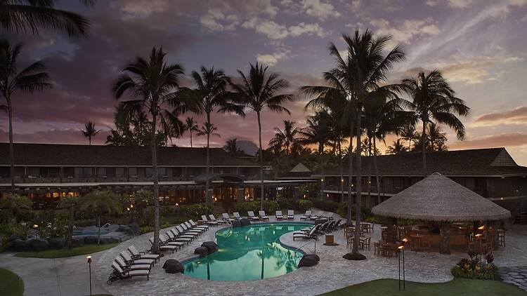 Courtyard at Koʻa Kea Resort on Poipu Beach with a pool and tiki-thatched pool bar