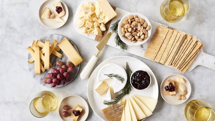A marble table with cheese plates, fruits and jams
