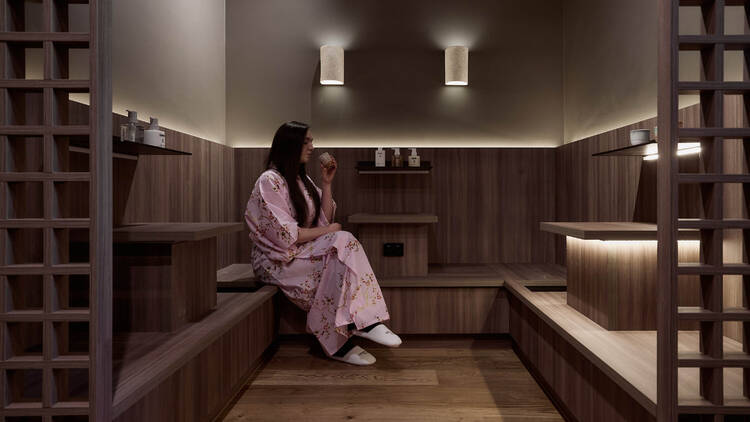 A person in a pink kimono sipping tea.