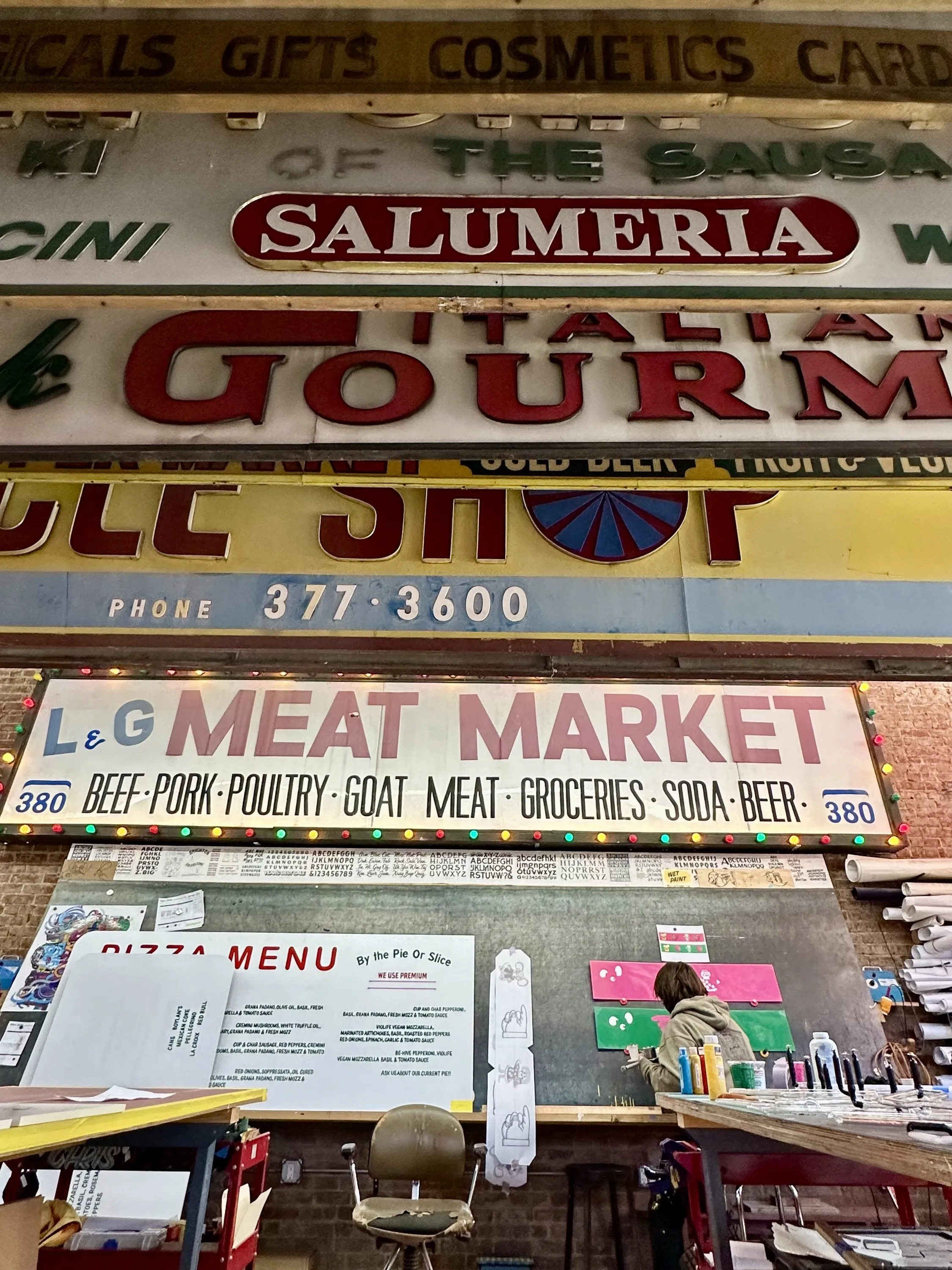 Signs hung up up in a sign museum above a painter at work.