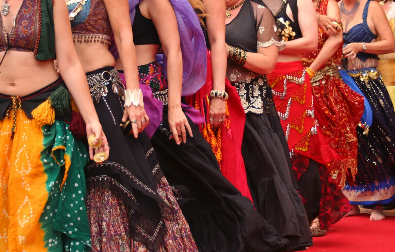 A row of belly dancers wearing colorful traditional clothing