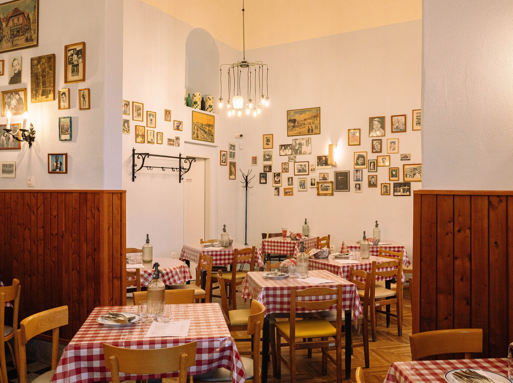 A Kádár Étkezde belső tere megterített kockás terítős asztalokkal, székekkel, képekkel a falon