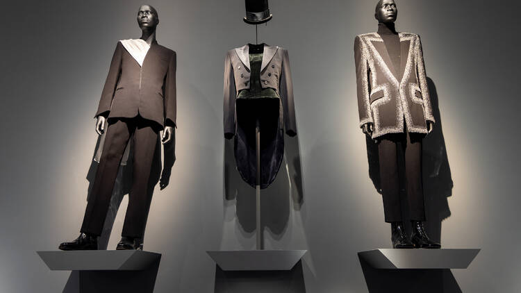Three mannequins display black suits. 