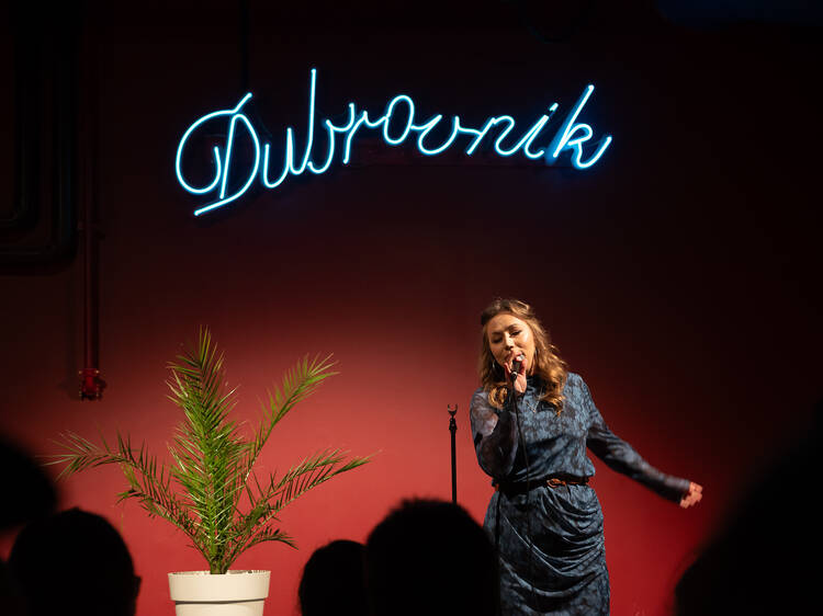 Nainen esittää stand up komediaa Helsingissä klubilla nimeltä Dubrovnik Nainen esittää stand up komediaa Helsingissä klubilla nimeltä Dubrovnik