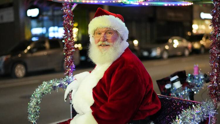 A person dressed up as Santa Claus sits in a pedicab. A person dressed up as Santa Claus sits in a pedicab.
