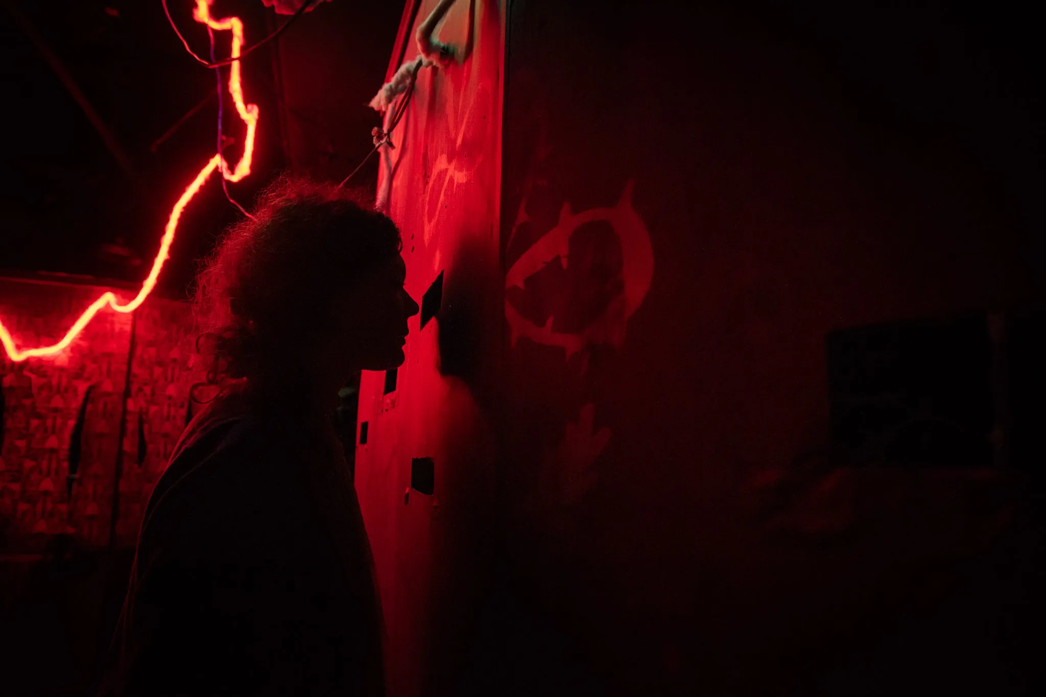 A visitor at House of the Exquisite Corpse V: Blood & Puppets peers through a peephole.