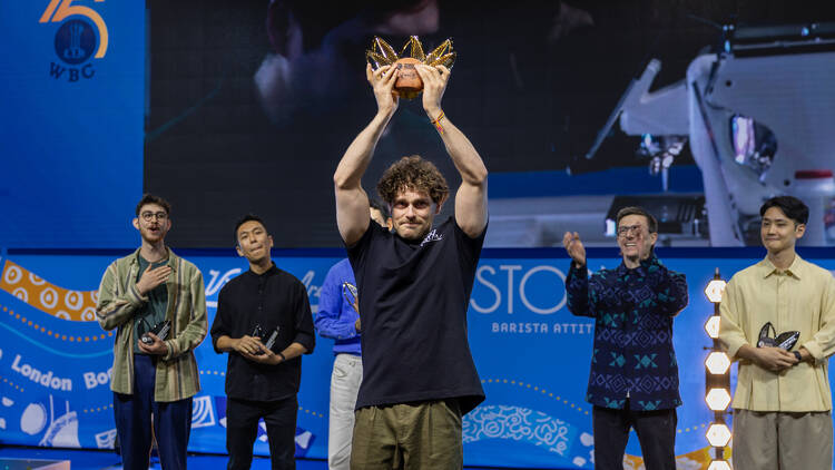 Barista Jack Simpson holding a trophy on stage.