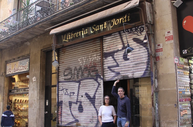 Judit Gim&eacute;nez i Rafa Serra levantan la persiana de la Llibreria Sant Jordi.