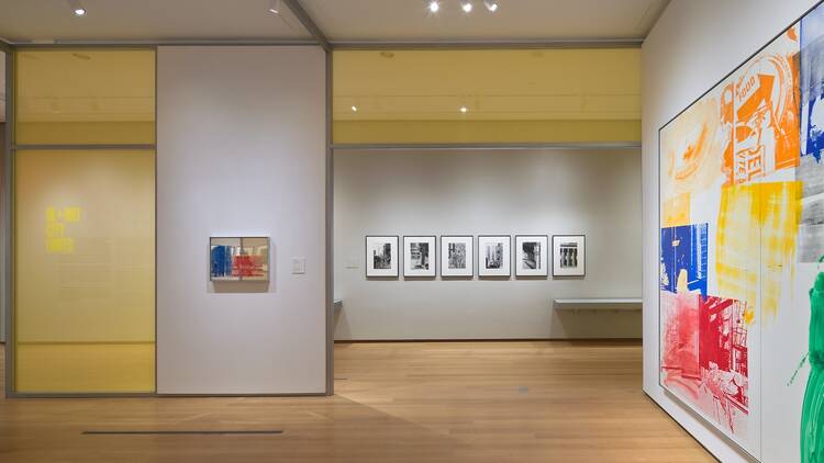 Photos are displayed on a wall inside a museum exhibition.  Photos are displayed on a wall inside a museum exhibition.