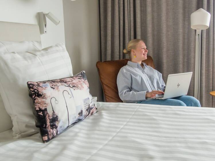 Cozy room at Sokos Hotel Ilves Tampere with striped bedding, artistic pillow, and workspace setup. Cozy room at Sokos Hotel Ilves Tampere with striped bedding, artistic pillow, and workspace setup.