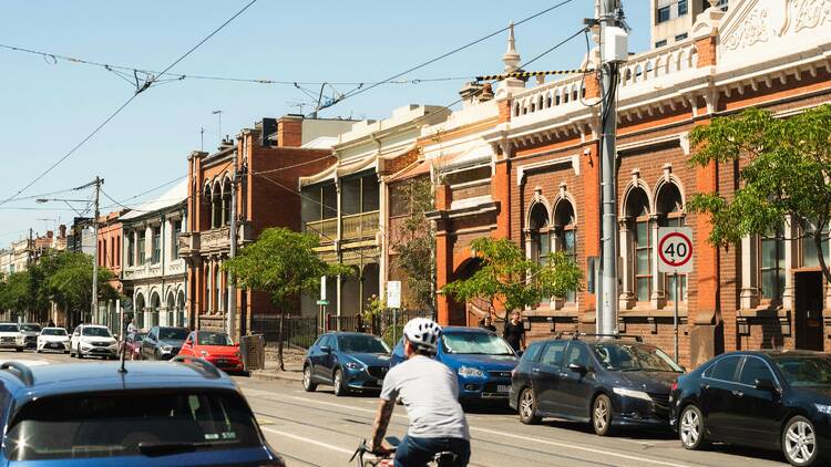 Melbourne street Man riding bike on street next to parked cars