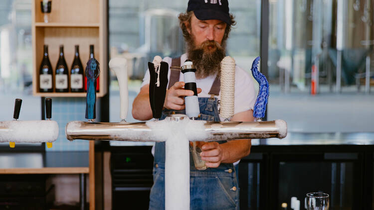 Dunetown A bearded man pouring a beer at Dunetown.