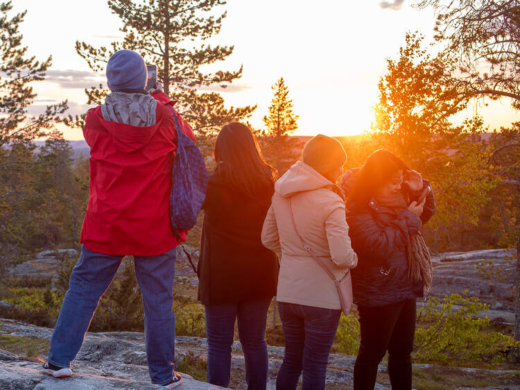Group of tourists marvelling the midnight sun at Ounasvaara fell, in Rovaniemi Group of tourists marvelling the midnight sun at Ounasvaara fell, in Rovaniemi