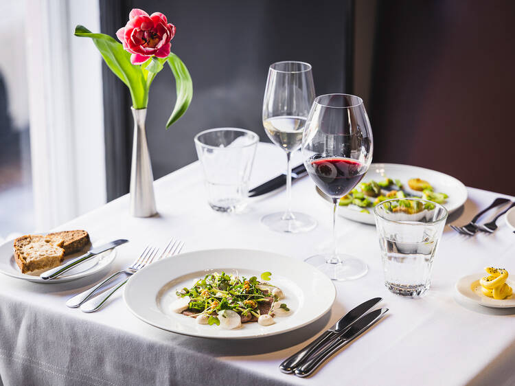 Annos ruokaa ja lasi viiniä valkoisella pöytäliinalla ravintola Vinkkelin lounaalla Helsingissä Annos ruokaa ja lasi viiniä valkoisella pöytäliinalla ravintola Vinkkelin lounaalla Helsingissä