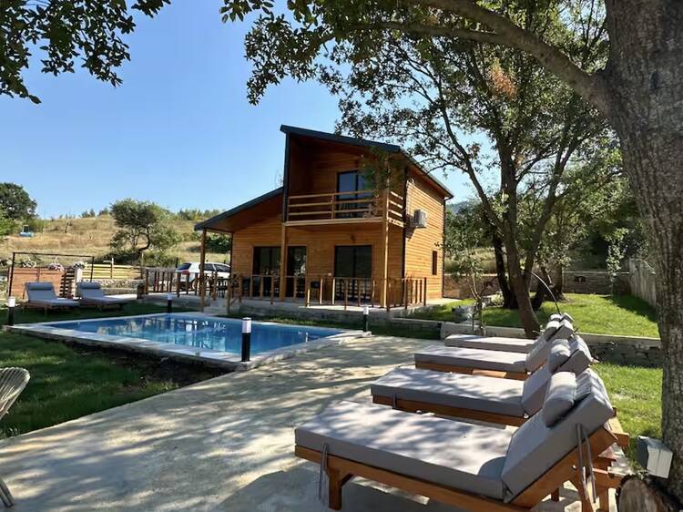 Photo of a large wooden chalet surrounded by a pool, terrace and sun loungers