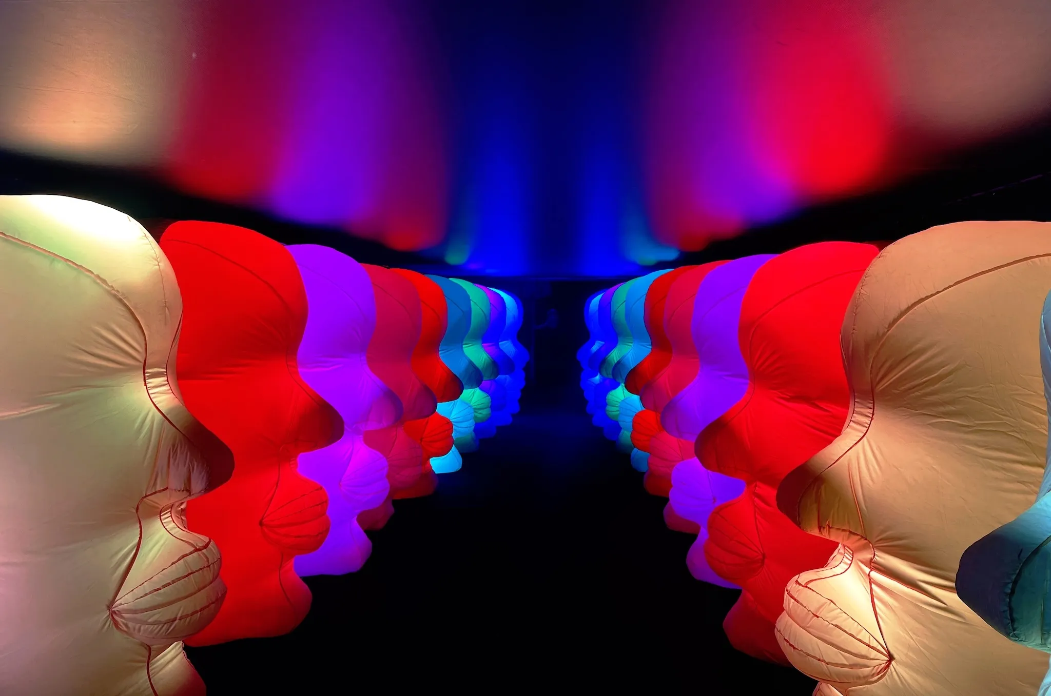 Inflated heads lining a dark hallway at the Balloon Museum's "EmotionAir" exhibition.