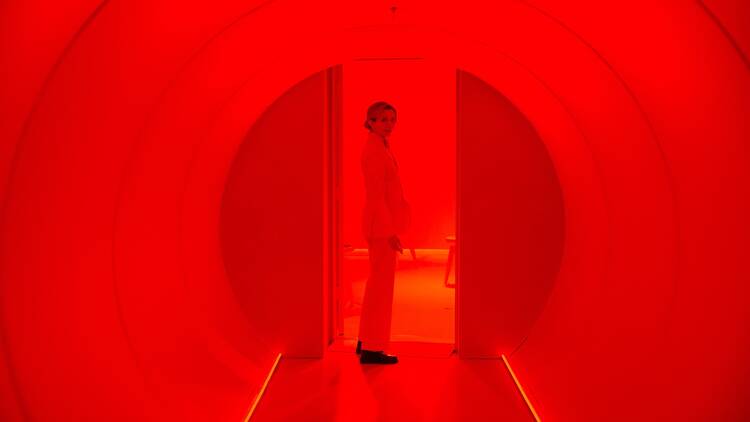 David Byrne's "Theater of the Mind" A "Theater of the Mind" guide stands at the end of a hallway washed in red light.