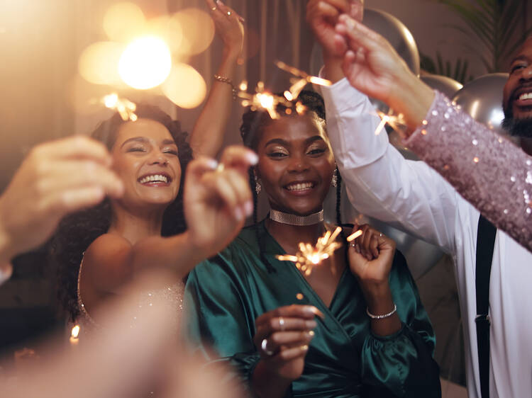 Business people, party and sparklers at night for celebration, diversity and happy for new year countdown. Women, men and smile for friends with fireworks, connection or cheers in group at gala event