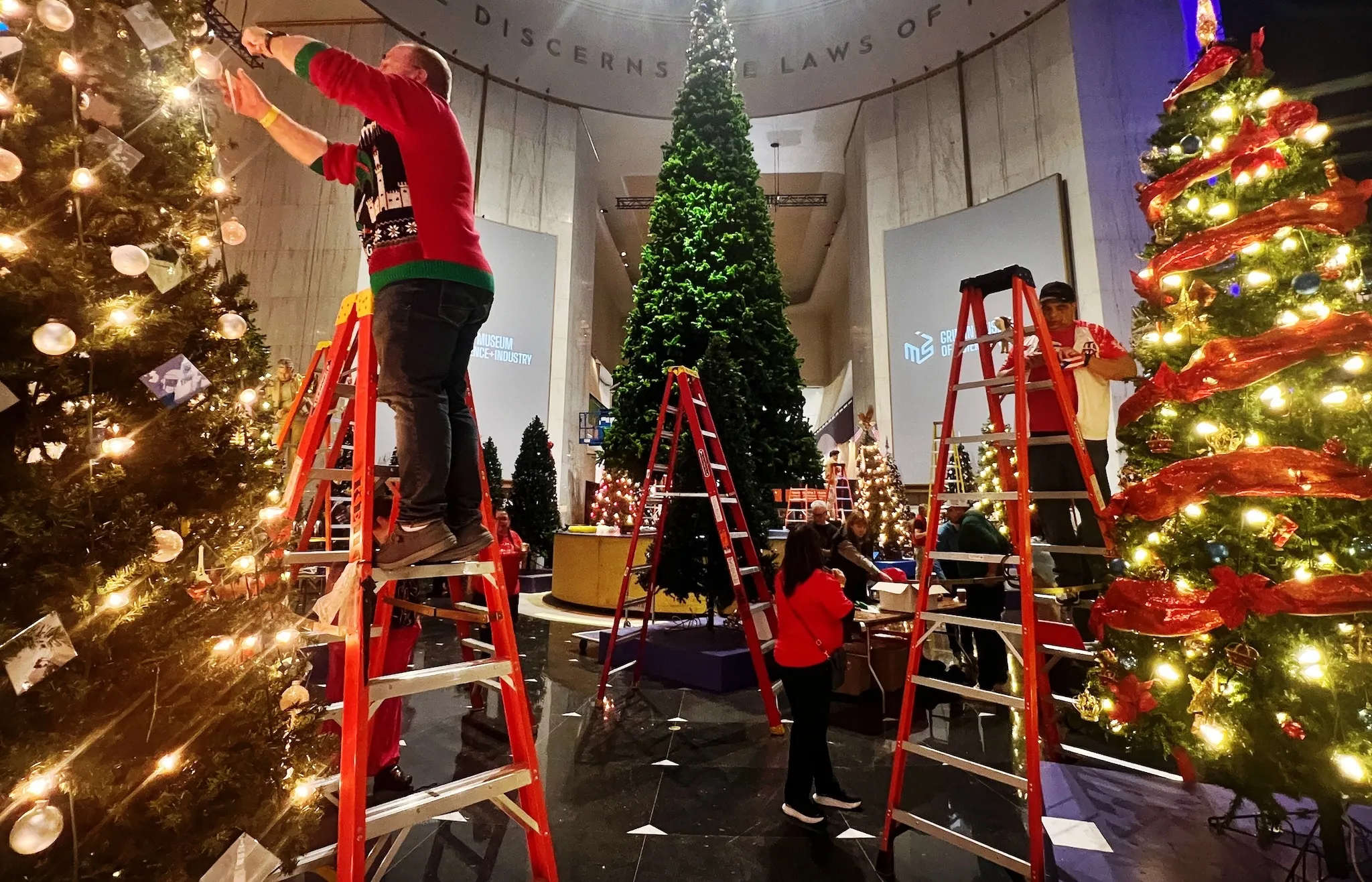 Volunteers decorate trees for the Griffin MSI's "Christmas Around the World and Holidays of Light" exhibition.