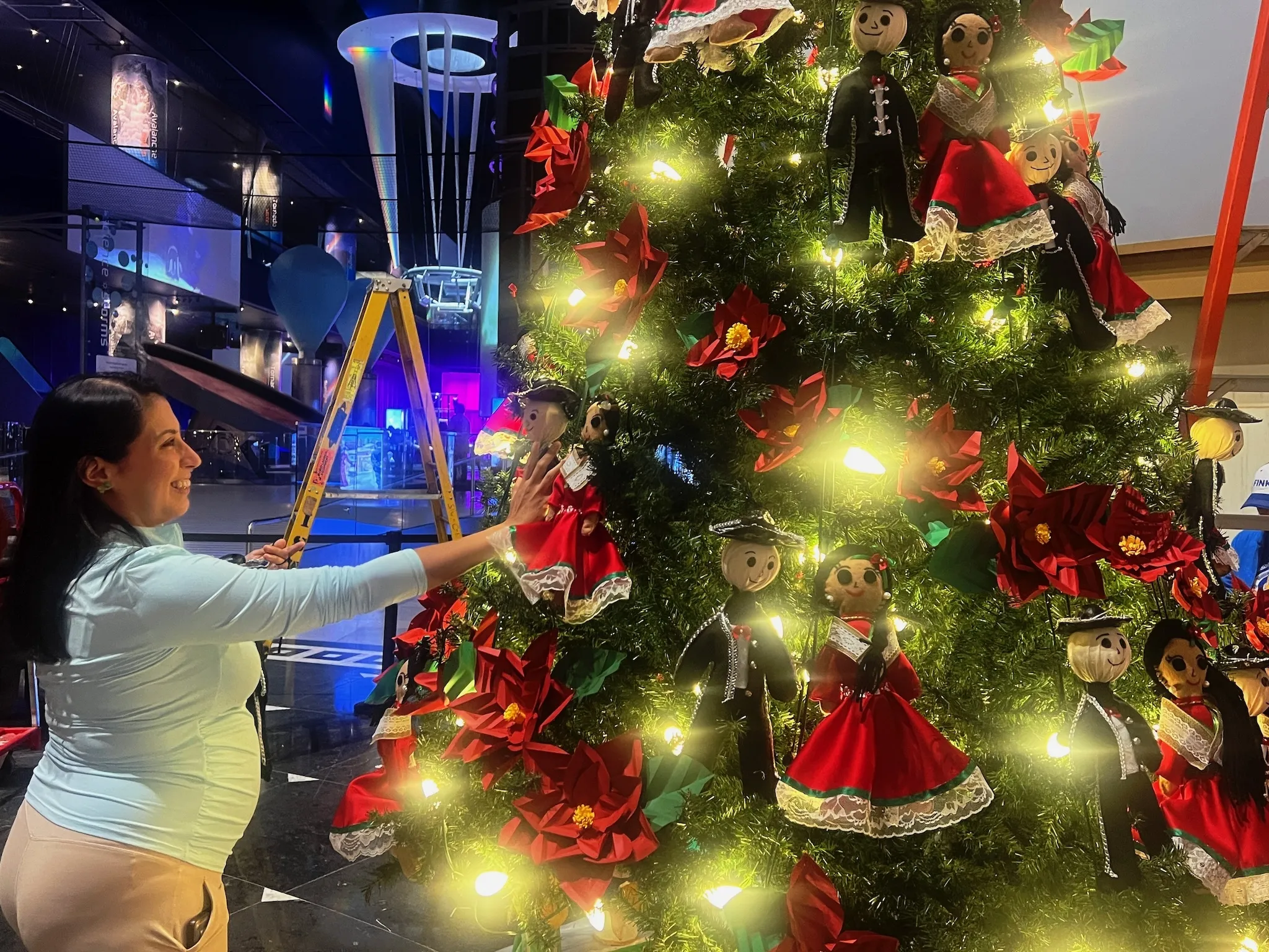 A volunteer decorates Mexico's tree for the Griffin MSI's "Christmas Around the World and Holidays of Light" exhibition.