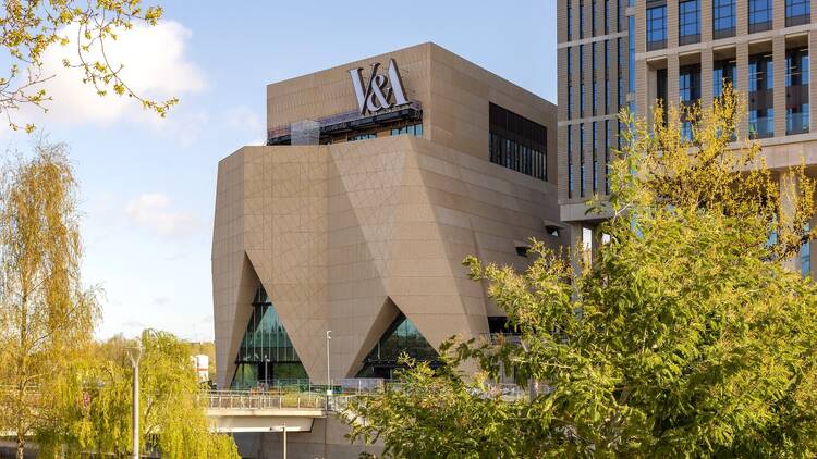 V&A East Museum Exterior of the V&A East, viewed from a distance and framed by trees in the foreground