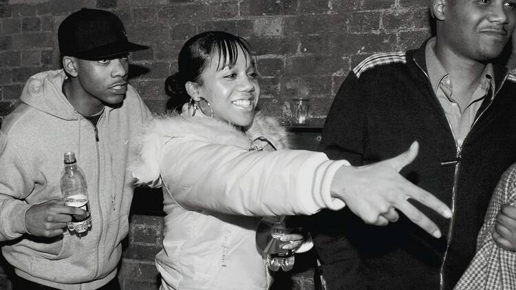 Nolay, London, 2005 A black and white photo of Nolay, a young female rapper of Carribean and Greek Cypriot heritage, flanked by two male friends