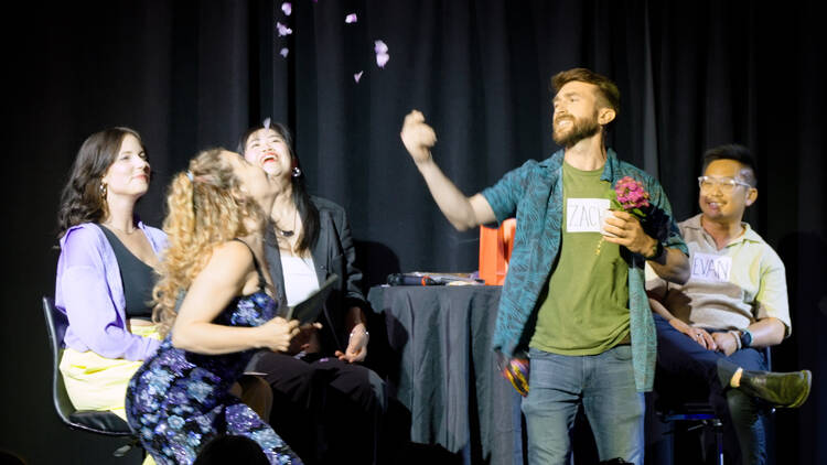 a man throwing rose petals into the air on stage with three other women a man throwing rose petals into the air on stage with three other women