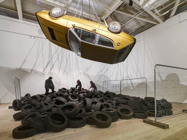 Yellow taxi suspended upside down over a pile of tyres Yellow taxi suspended upside down over a pile of tyres