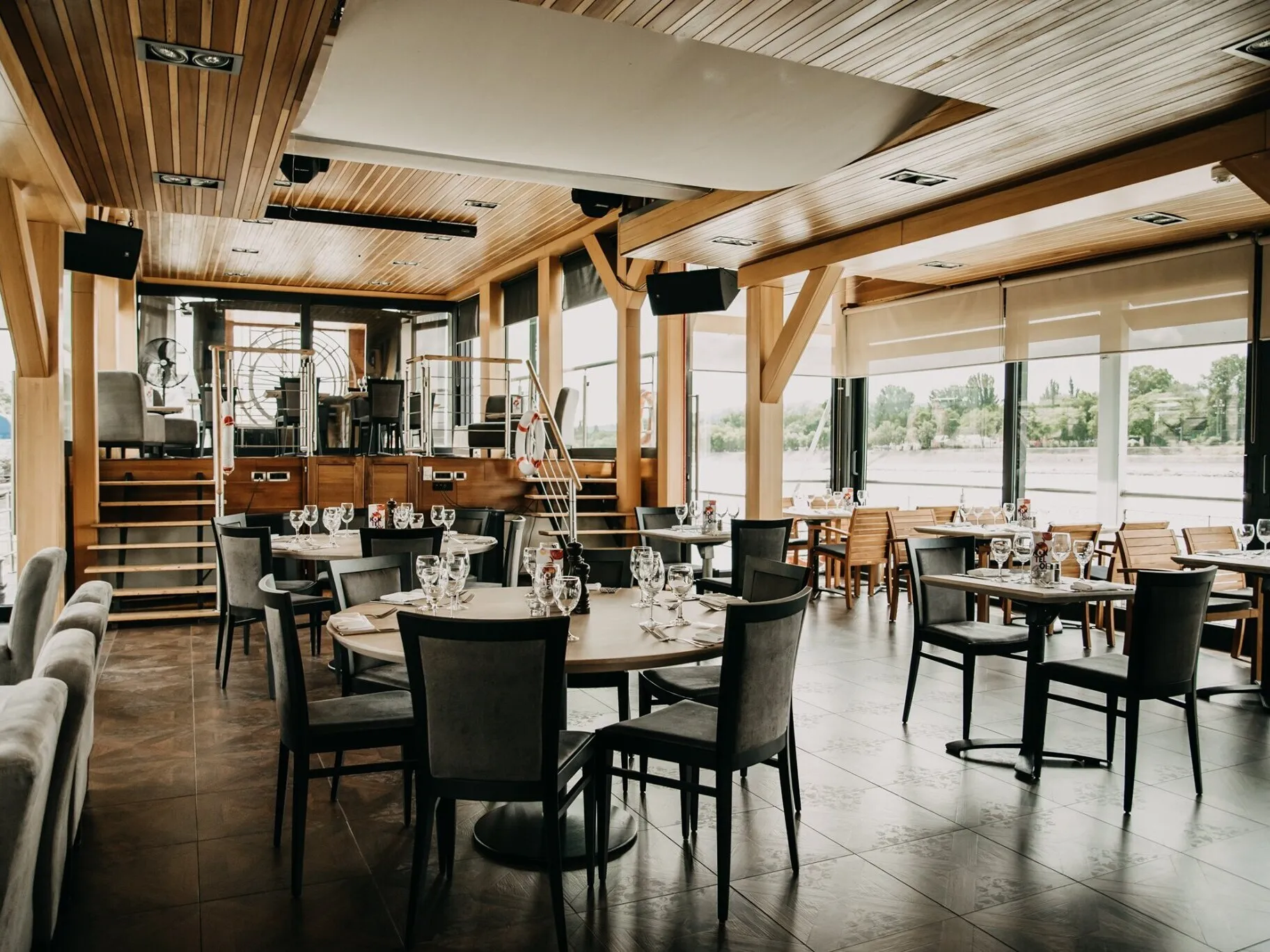 A Vogue Étteremhajó belső tere, enteriőrje asztalokkal, székekkel, kilátással a Dunára és a budai hegyekre