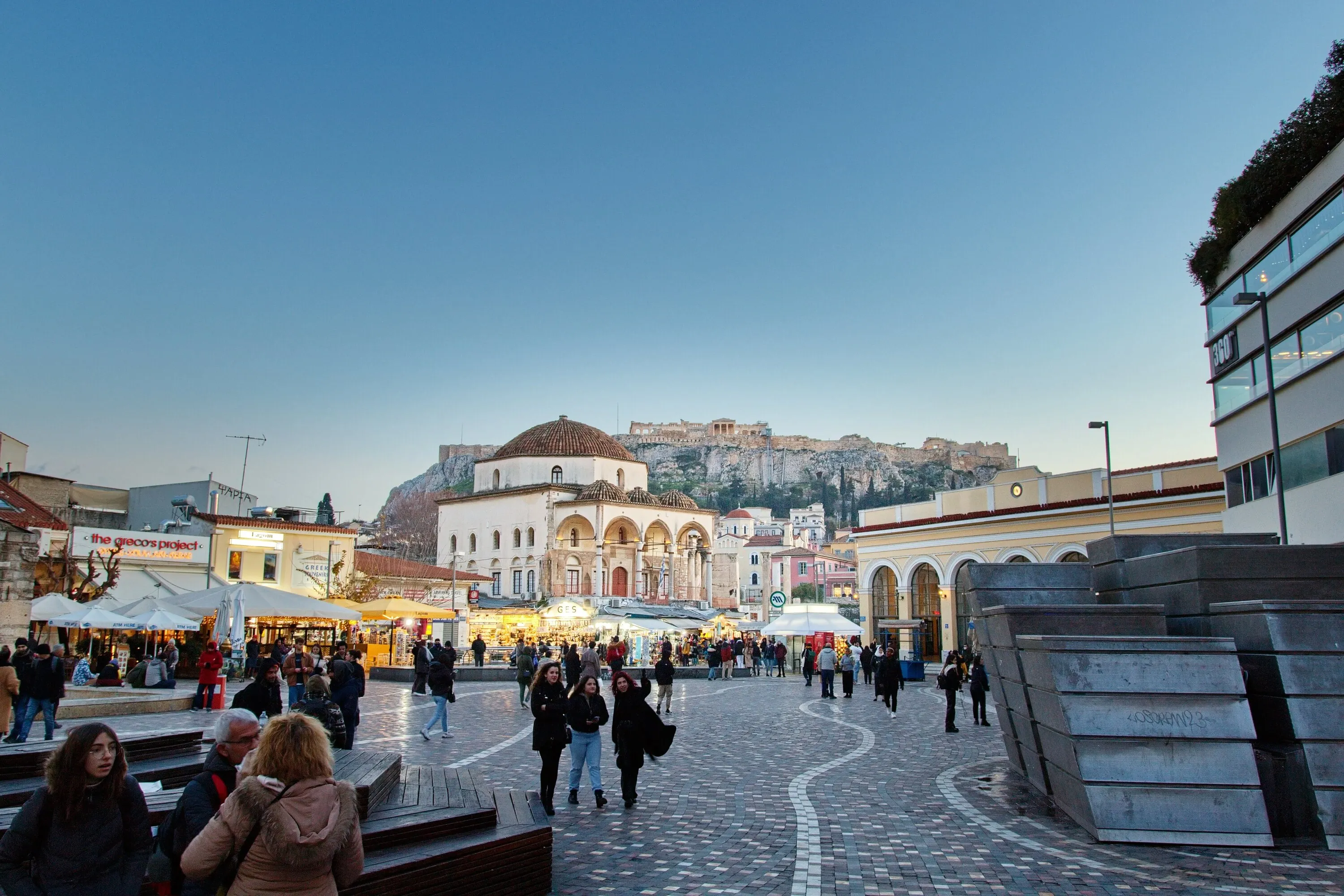 Square Monastiraki in heart of Plaka full of people with Acropolis in background during sunset on winter holiday