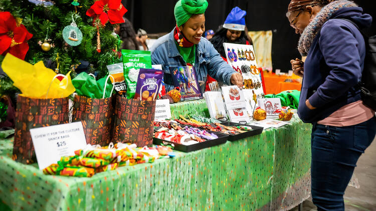 A woman purchasing goods at a holiday market vendor A woman purchasing goods at a holiday market vendor