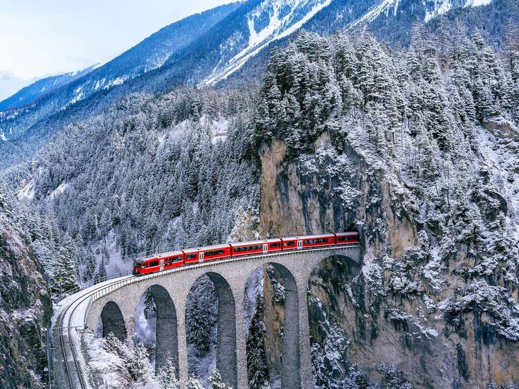Snow falling and Train passing through famous mountain in Filisur, Switzerland. Train express in Swiss Alps snow winter scenery. Snow falling and Train passing through famous mountain in Filisur, Switzerland. Train express in Swiss Alps snow winter scenery.