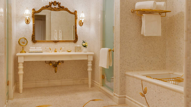 A bathroom in a hotel room with a large sink, glass shower and tub.