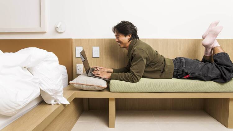 A man lying on a day bed with a laptop