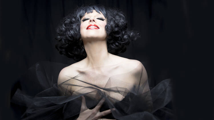 A woman performing on stage to a black background