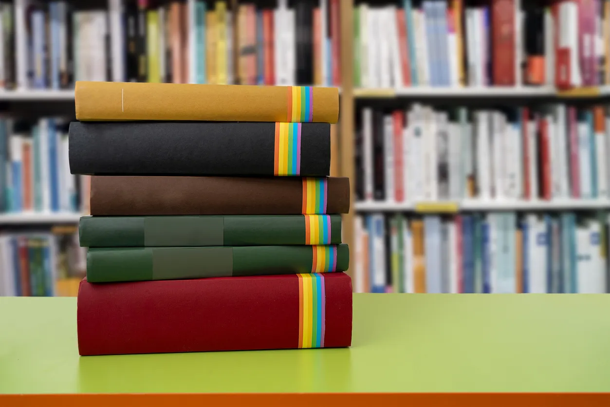 Close up of books on desk in library with LGBTQ rainbow flag