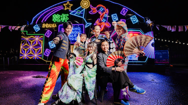 A group of Japanese magicians standing in front of neon lights