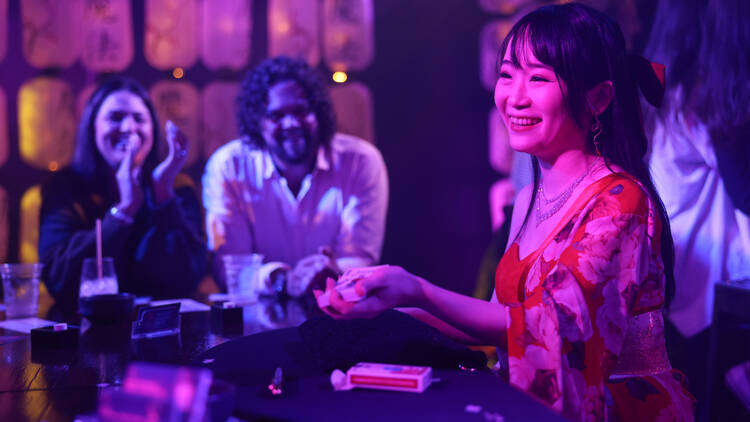 A woman performing up close magic at a bar