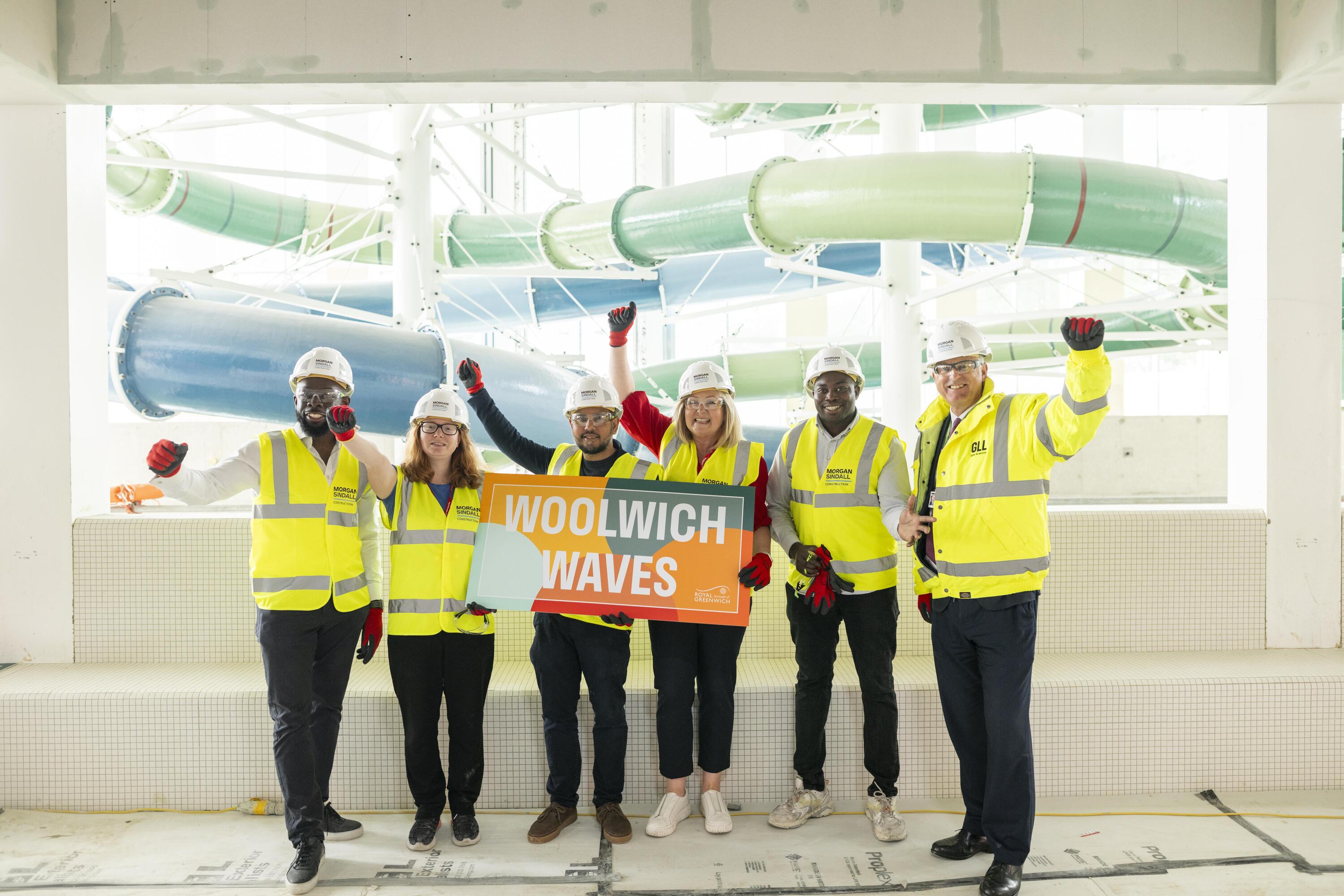 Photo of a team of people in high vis jackets and hardhats by a water slide