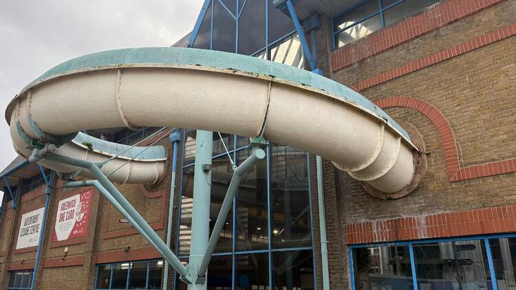 Photo of a rusty waterslide coming out of a leisure complex