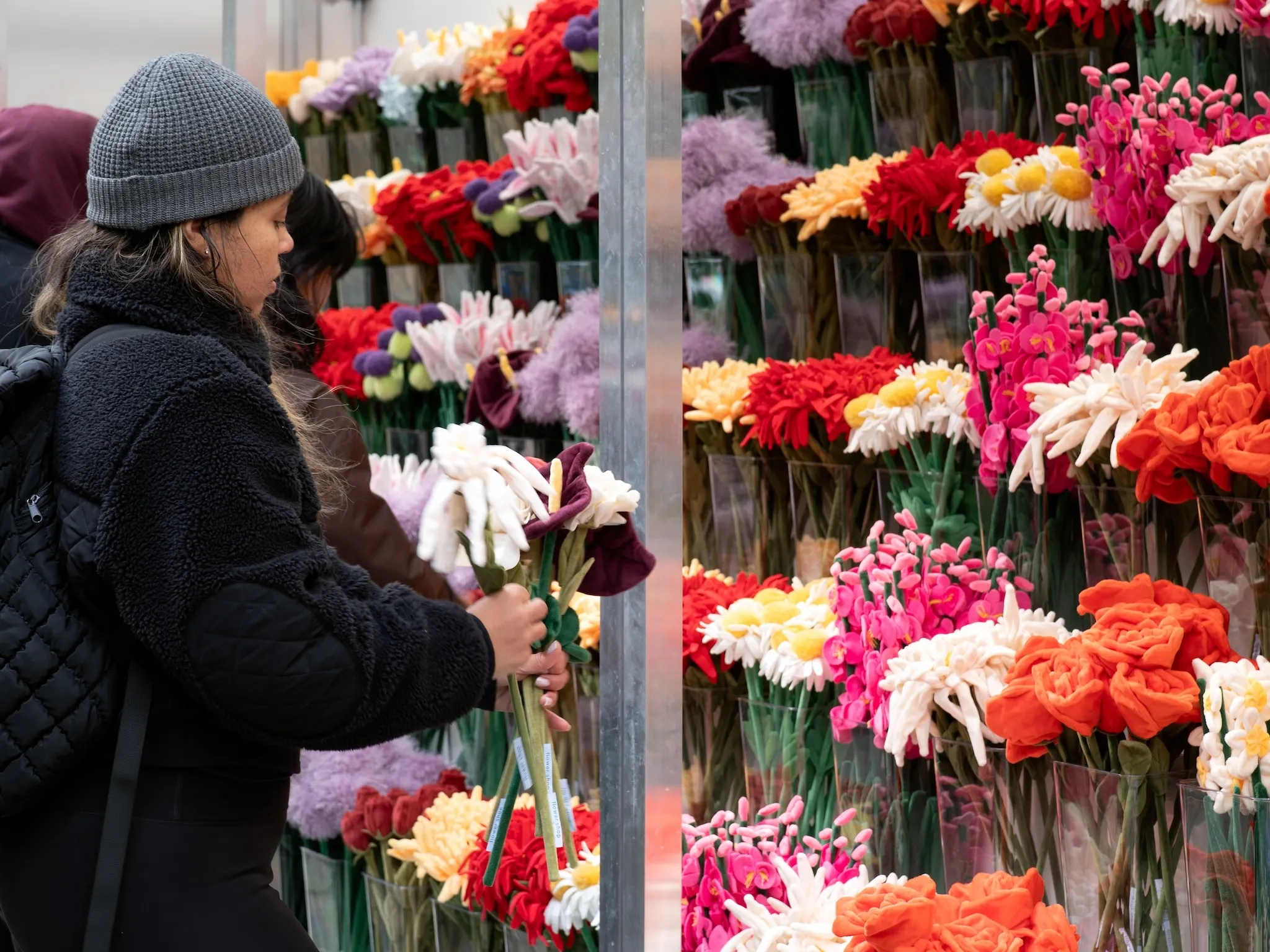 A woman picks up felt flowers at a floral pop-up.