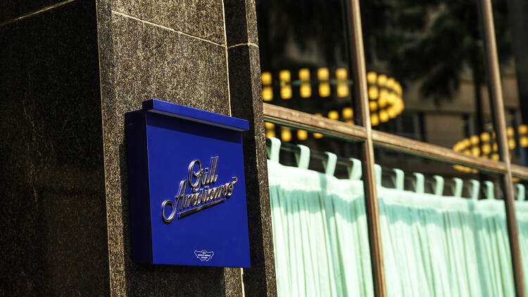 A blue sign on a wall that says 'Grill Americano'