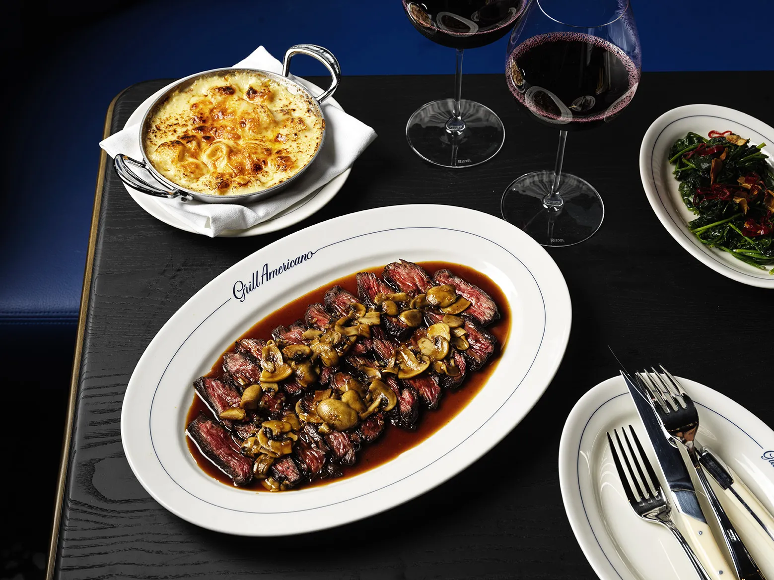 A sliced up steak with jus and mushrooms on a big plate